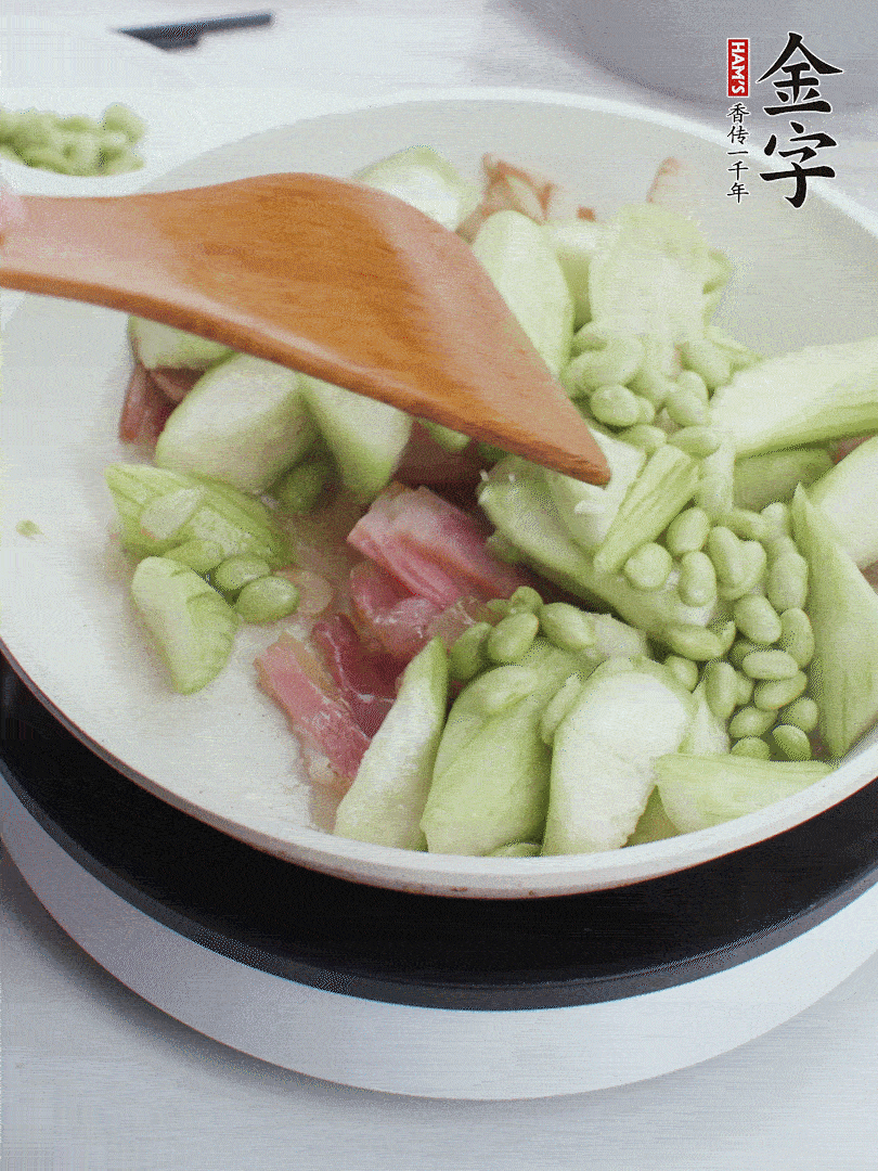依次下絲瓜、青豆翻炒，炒至絲瓜打蔫縮小。